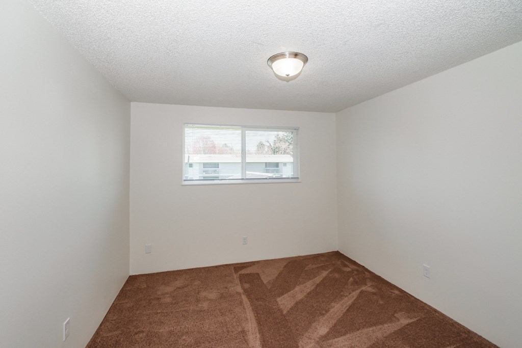 a bedroom with a window and a carpeted floor