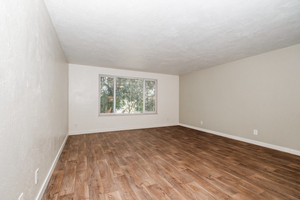 a bedroom with hardwood floors and a large window