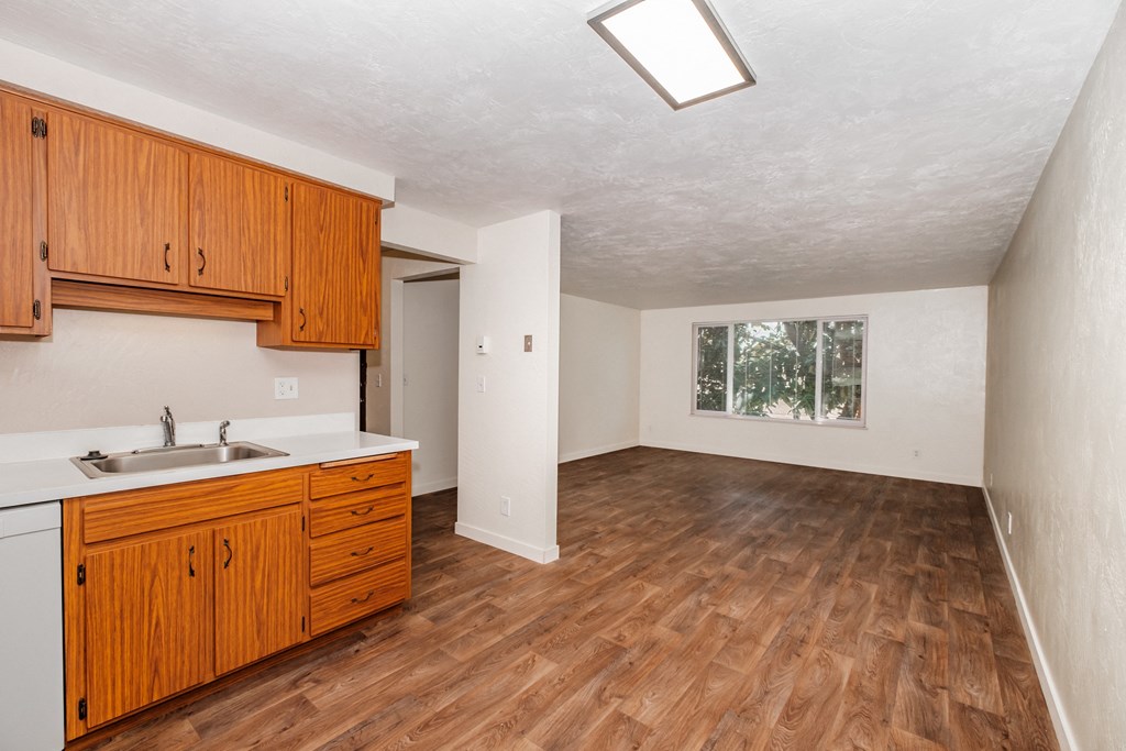 a kitchen and living room with hardwood floors and white walls