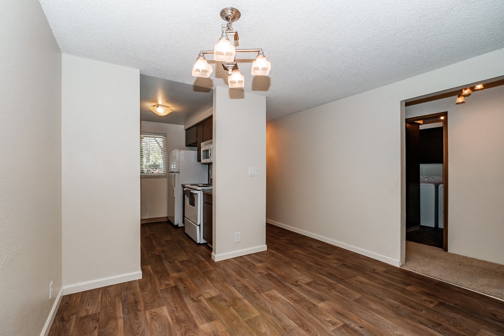 a living room with hardwood floors and a kitchen in the background