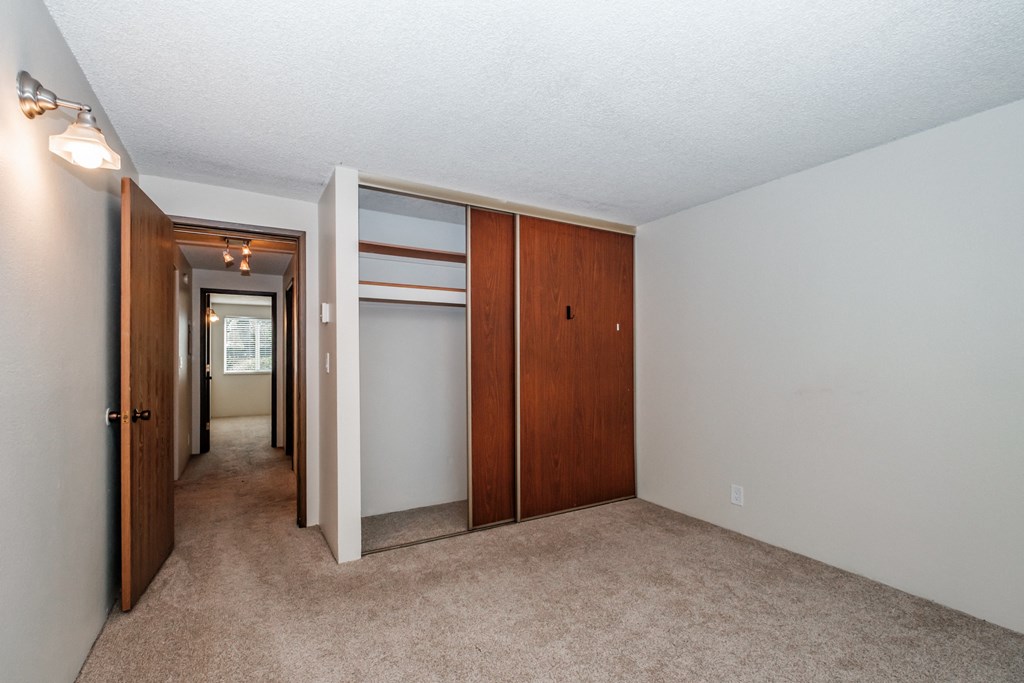 a bedroom with a carpeted floor and a closet with a mirrored door