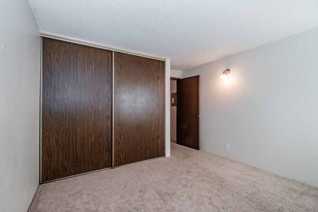an empty bedroom with a wardrobe and an open door
