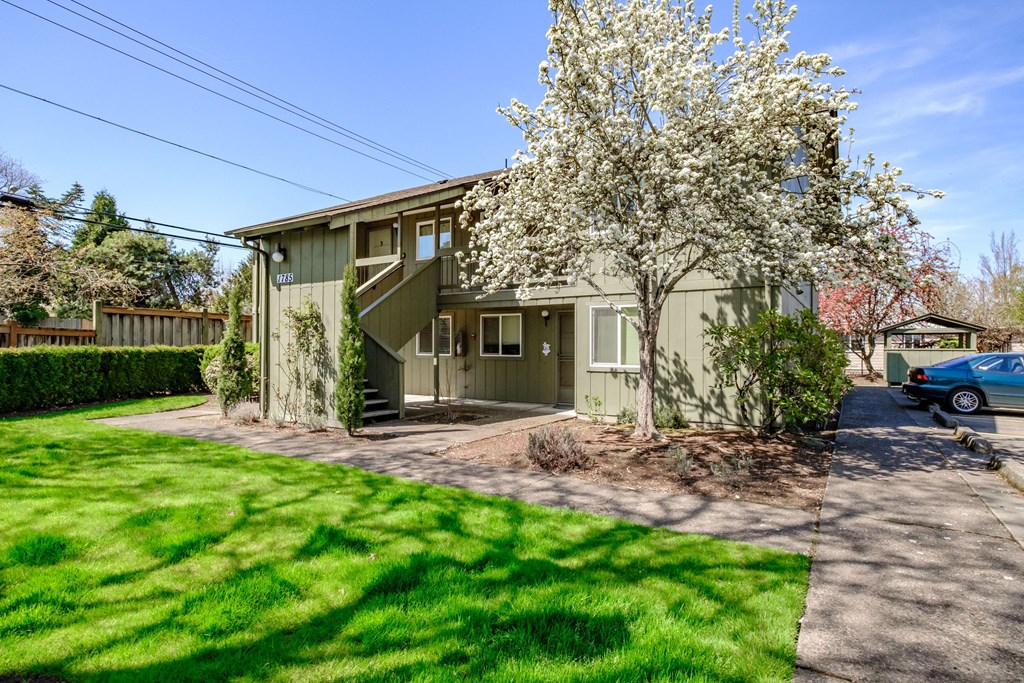 a green two story house with a tree in front of it