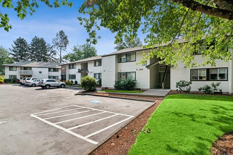 A parking lot in front of a building with a green lawn.