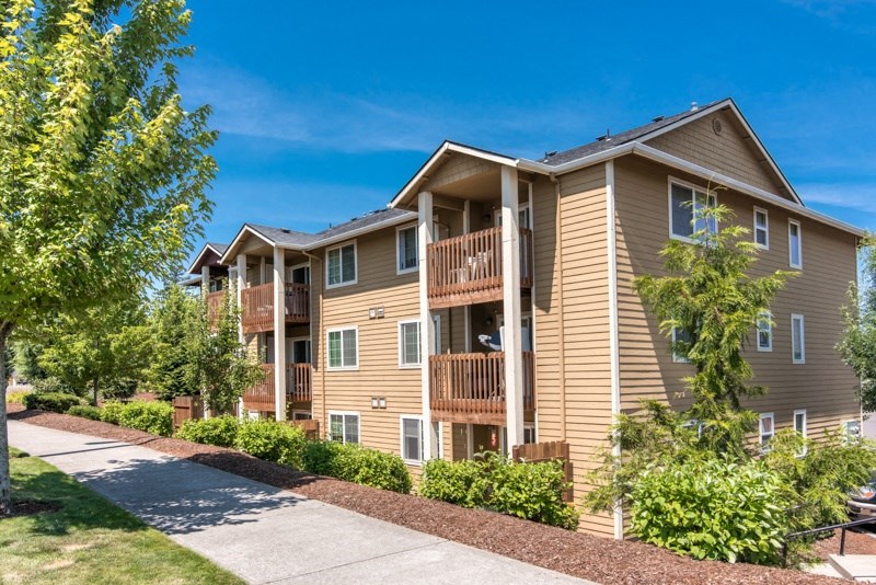 an apartment building with a sidewalk and trees