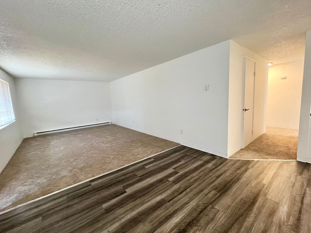an empty living room with wood flooring and white walls