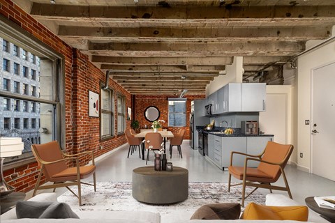 a living room with exposed brick walls and a kitchen with a table and chairs