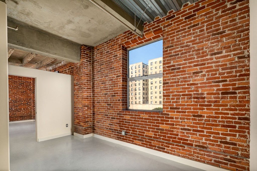 a large window in a room with a concrete floor and a brick wall