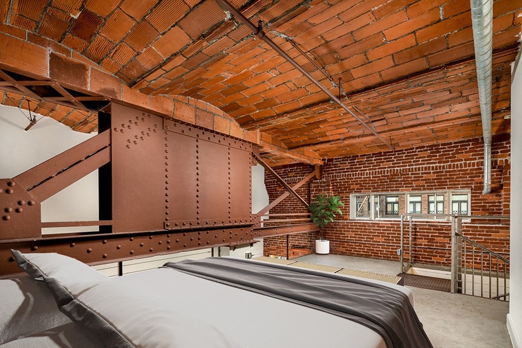 a bedroom with a bed and a exposed brick ceiling