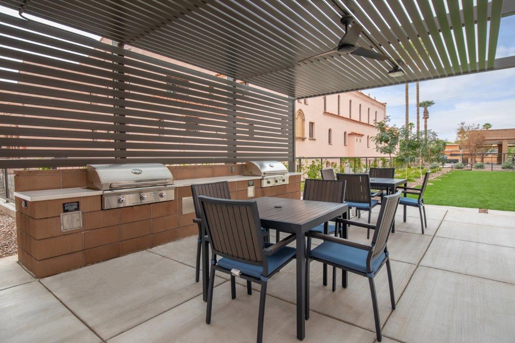 A patio with a table and chairs and a grill.