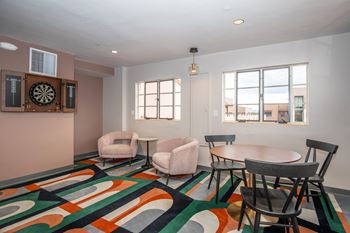 A room with a dart board on the wall and a colorful carpet.