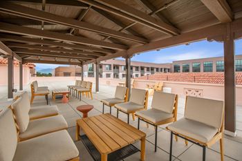 A patio with wooden furniture and a roof.