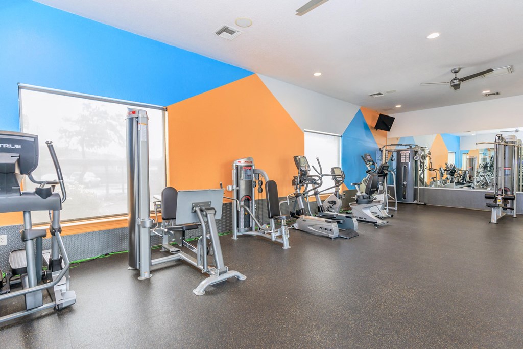 A gym with a variety of equipment including treadmills, weights, and exercise machines.