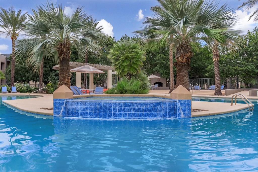 A pool surrounded by palm trees and a gazebo.