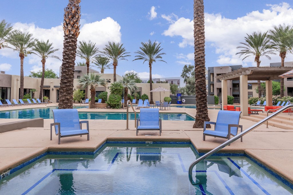 A pool surrounded by palm trees and lounge chairs.