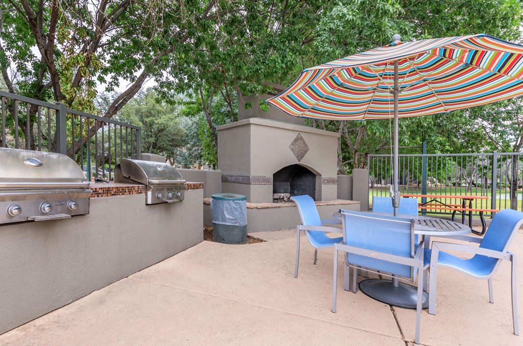 A patio with a table, chairs and an umbrella.