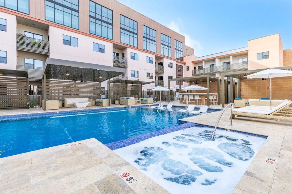 A large outdoor swimming pool with a hot tub in the middle of it.
