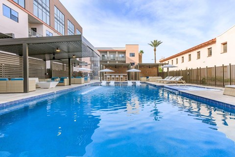 A large indoor swimming pool with a sunny day outside.