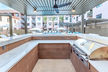 A modern outdoor kitchen with a built-in grill and seating area.