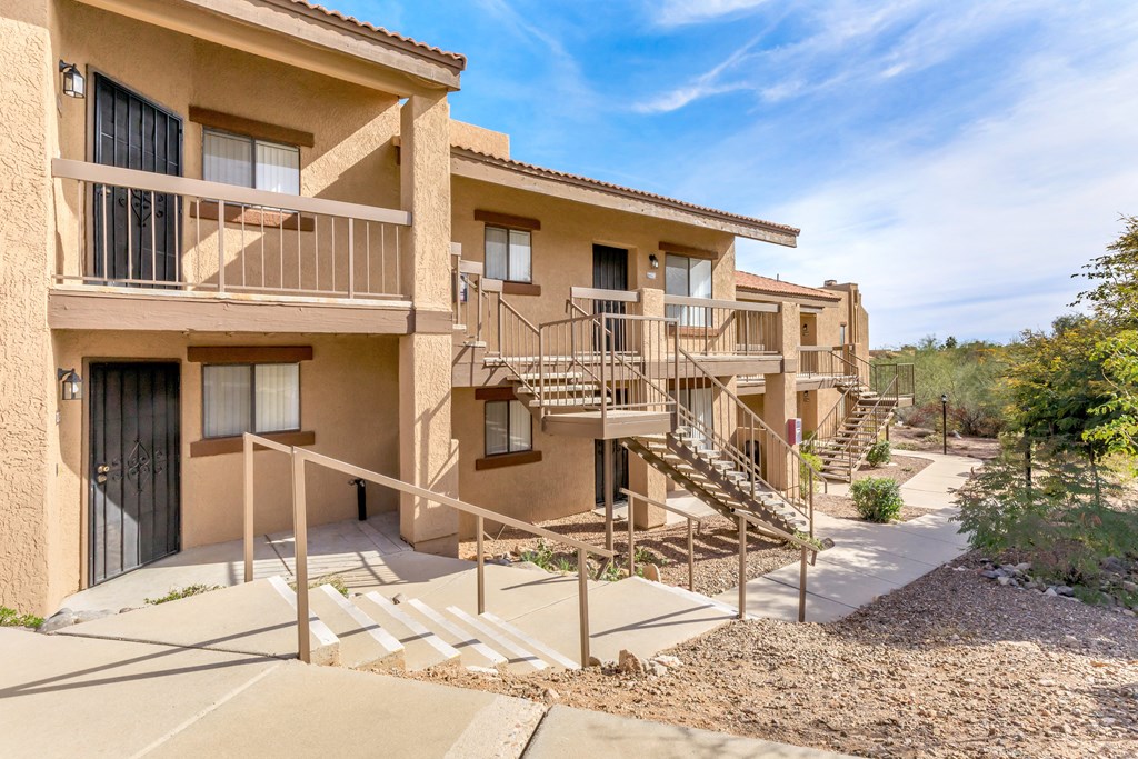 A sunny day at a beige apartment complex with a clear blue sky.
