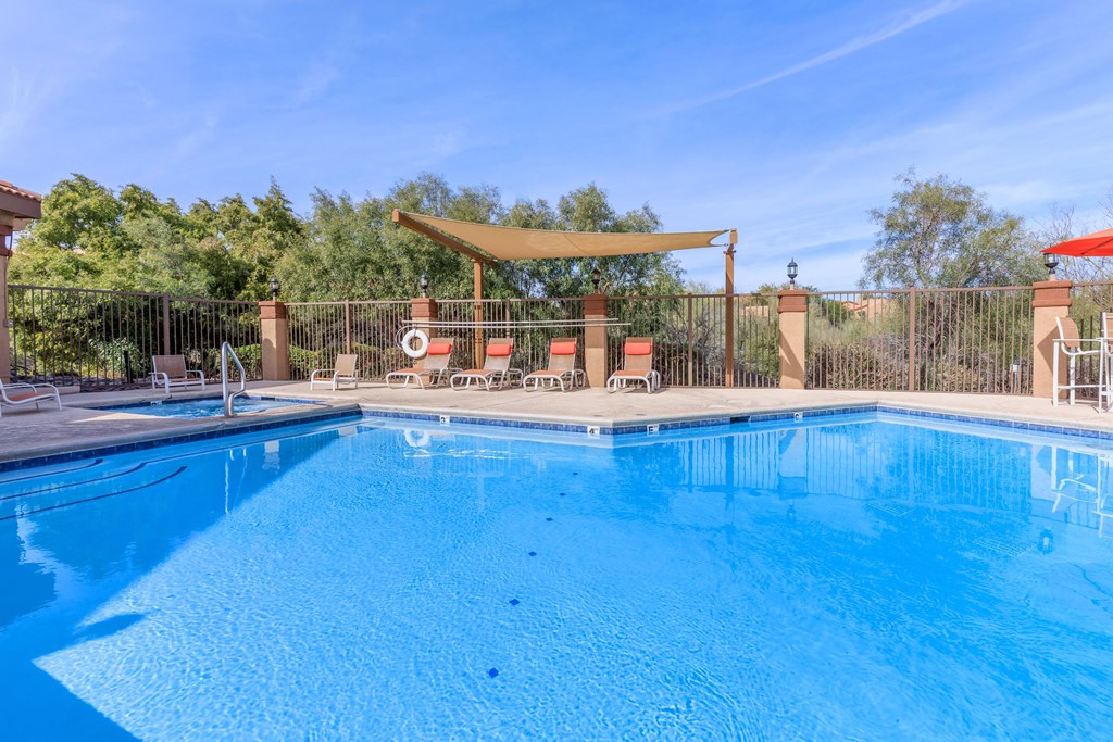 A large blue swimming pool with a sun lounger and umbrella.