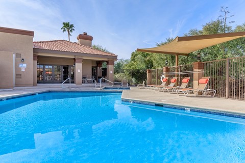 A swimming pool with a sun lounger and a building in the background.