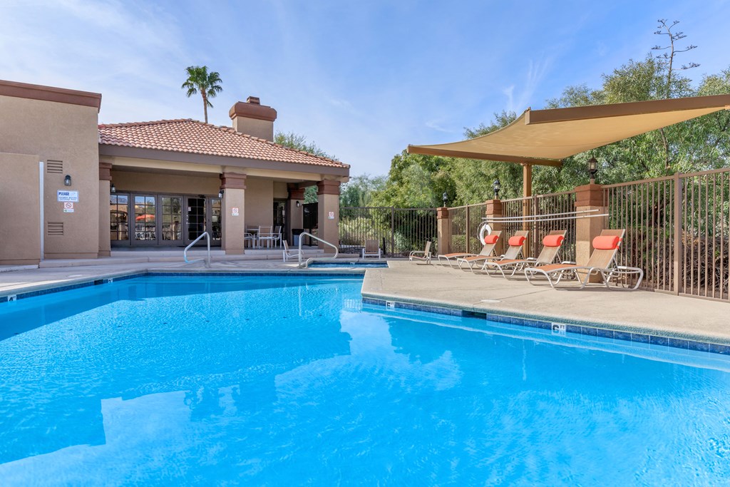 A swimming pool with a sun lounger and a building in the background.