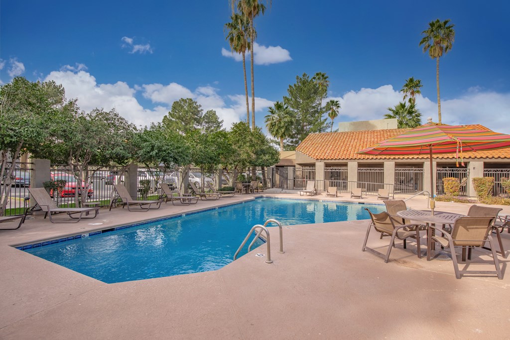 A pool with chairs and a building in the background.
