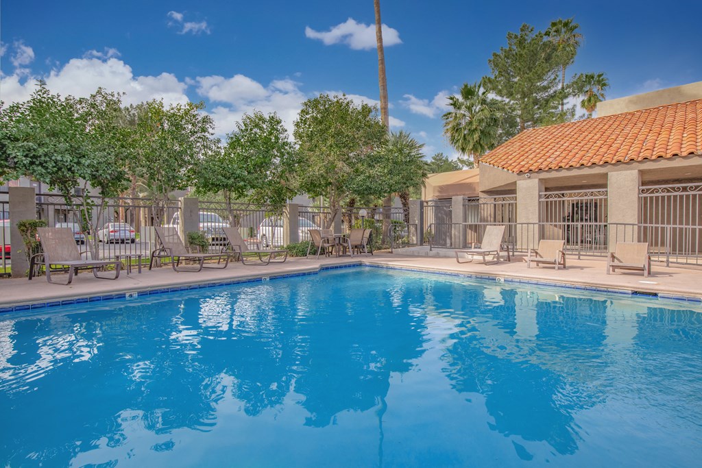 A large swimming pool with a blue tiled wall and a red roofed building in the background.