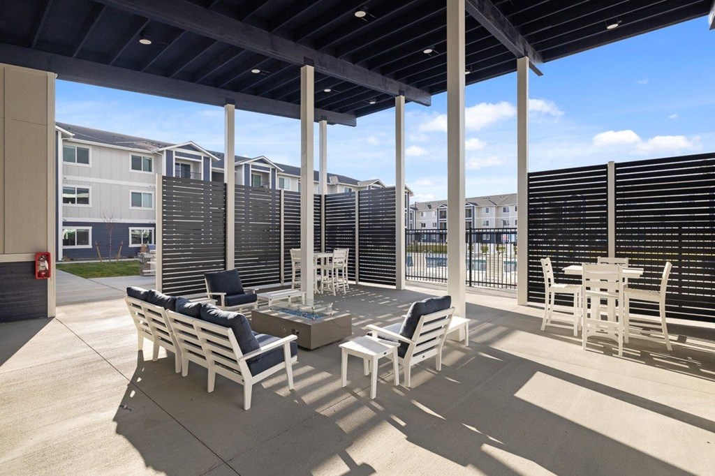 A patio with white furniture and a black awning.