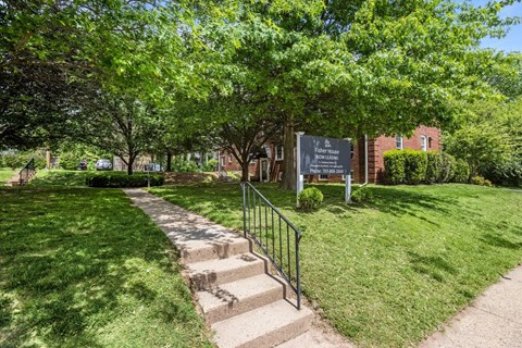 A sign in a park with a staircase leading to a building.