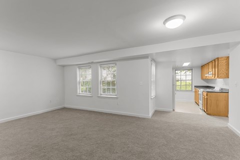 A spacious room with a carpeted floor and a window with blinds.