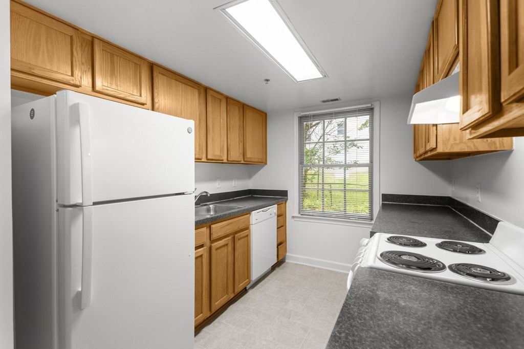 A white refrigerator is in a kitchen with wooden cabinets.