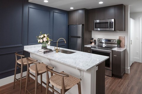 A kitchen with dark blue cabinets and a white marble countertop.