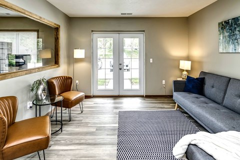 A living room with a grey couch, two chairs, and a rug.