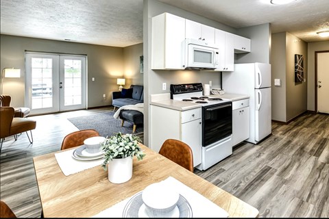 A modern kitchen with white appliances and a dining table set for two.