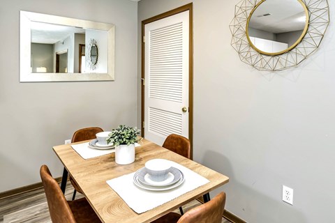 A dining room with a wooden table set for two.
