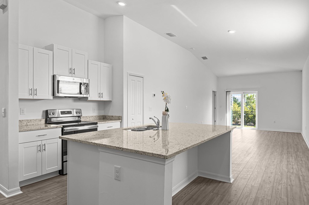 A kitchen with white cabinets and a granite countertop.
