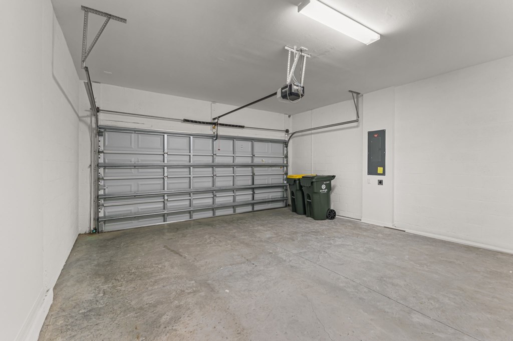 A large, empty garage with a lift and a trash bin.