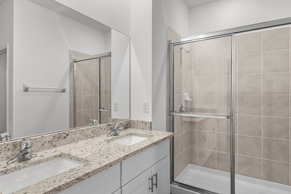 A bathroom with a walk-in shower and double sinks.