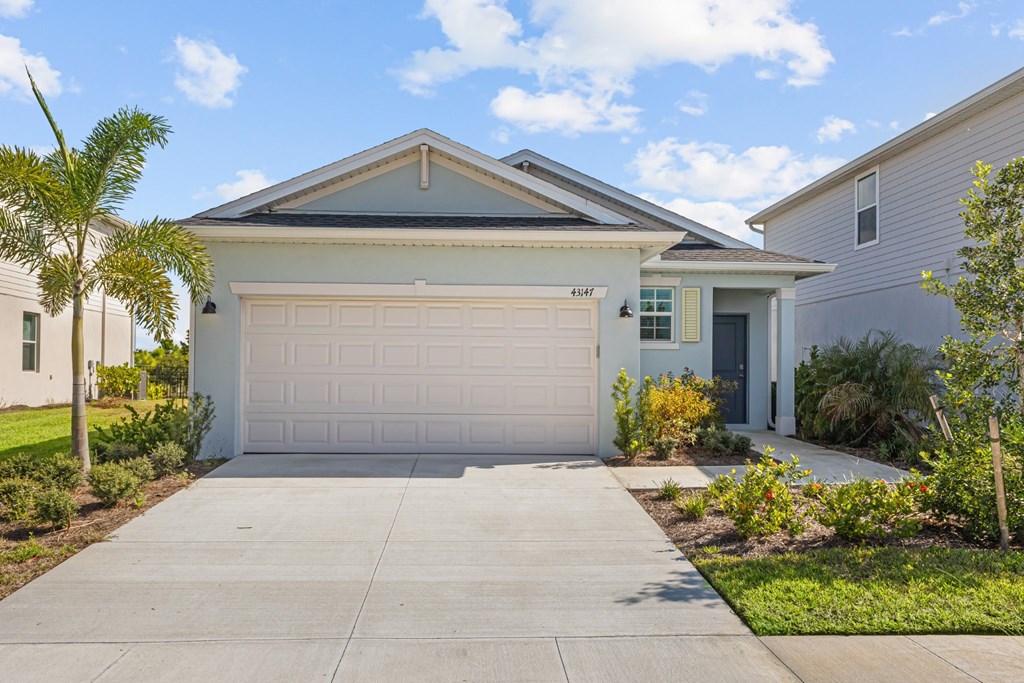 A house with a white garage door is surrounded by greenery.