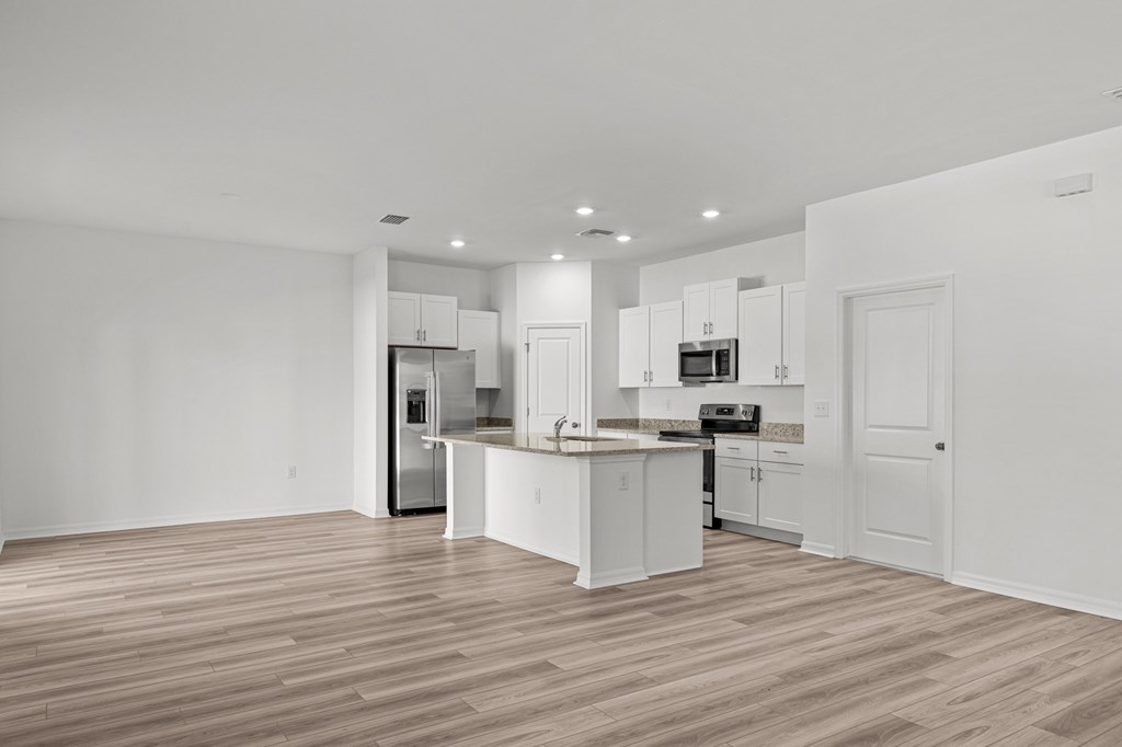 A kitchen with white cabinets and a wooden floor.