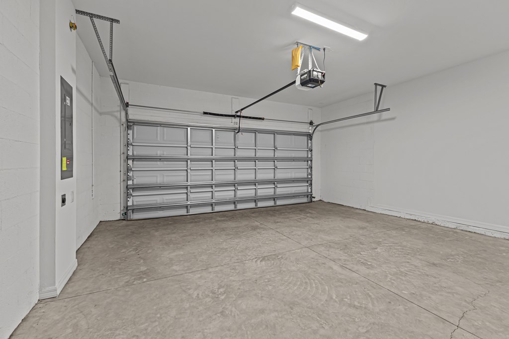 A garage with a closed shelving unit and a hanging light fixture.