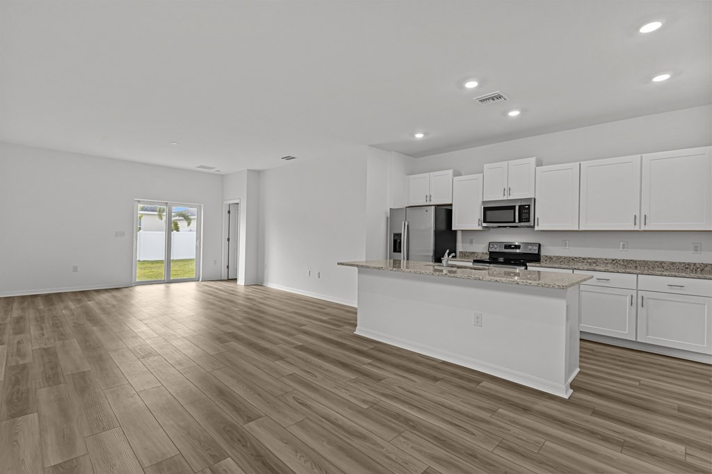 A kitchen with white cabinets and a wooden floor.