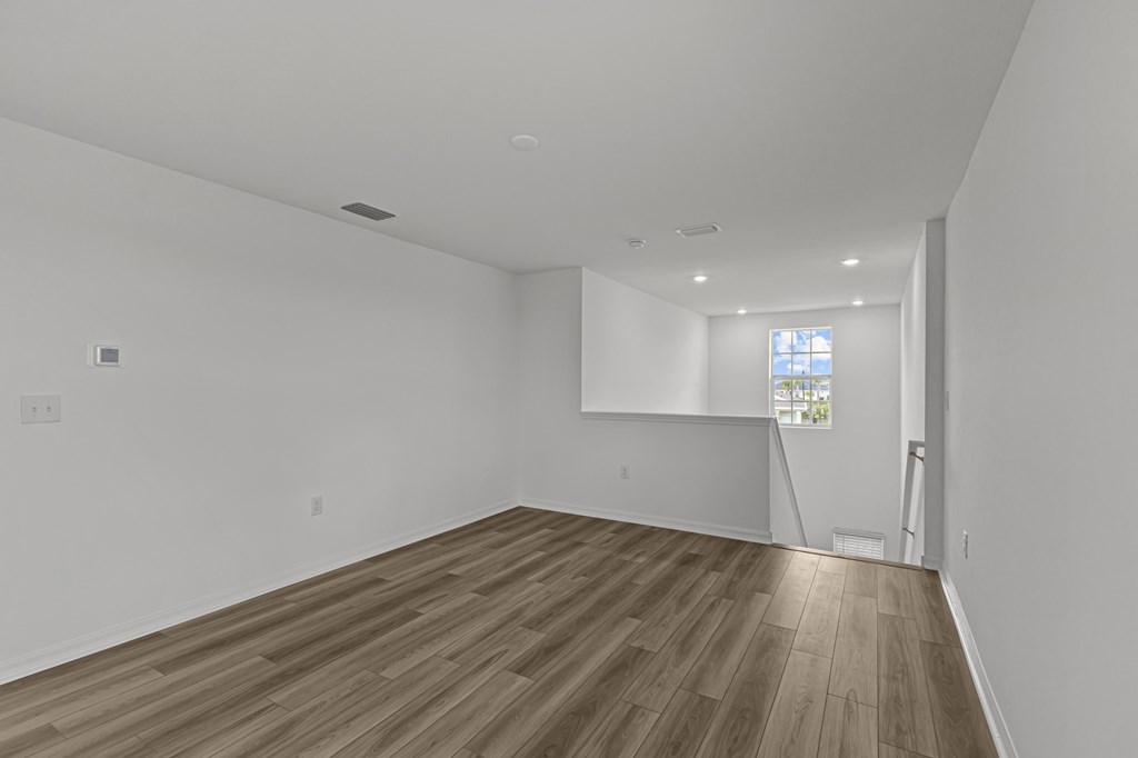 Empty room with wooden flooring and white walls.