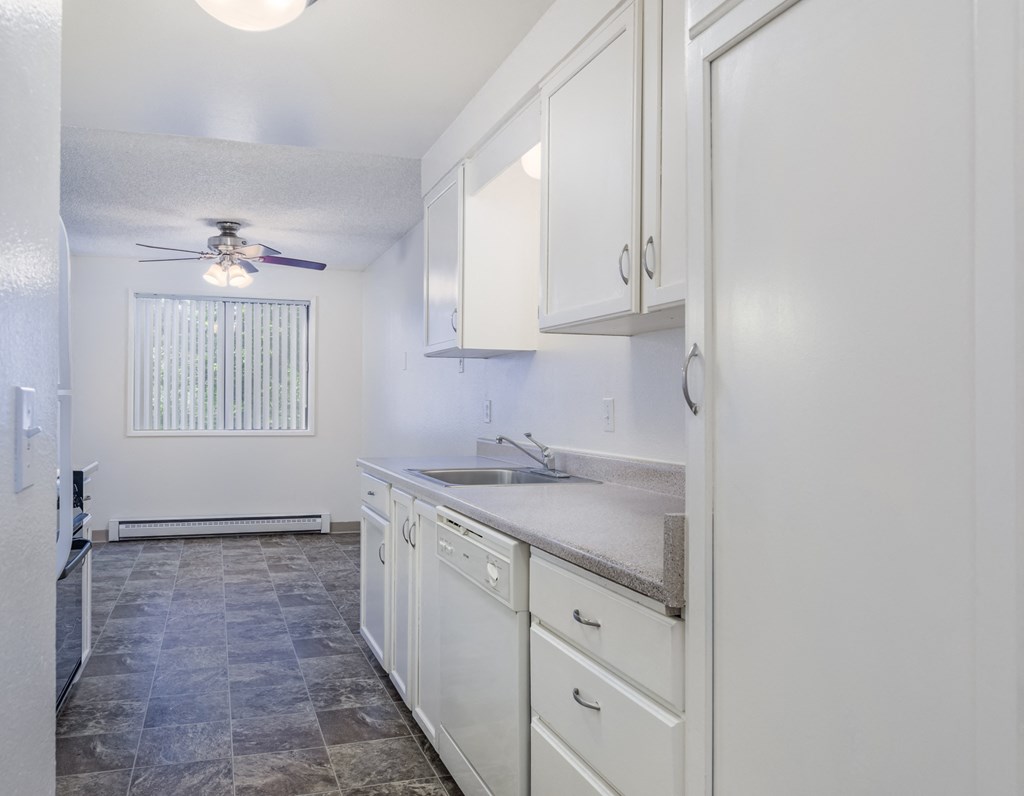 an empty kitchen with white cabinets and a ceiling fan