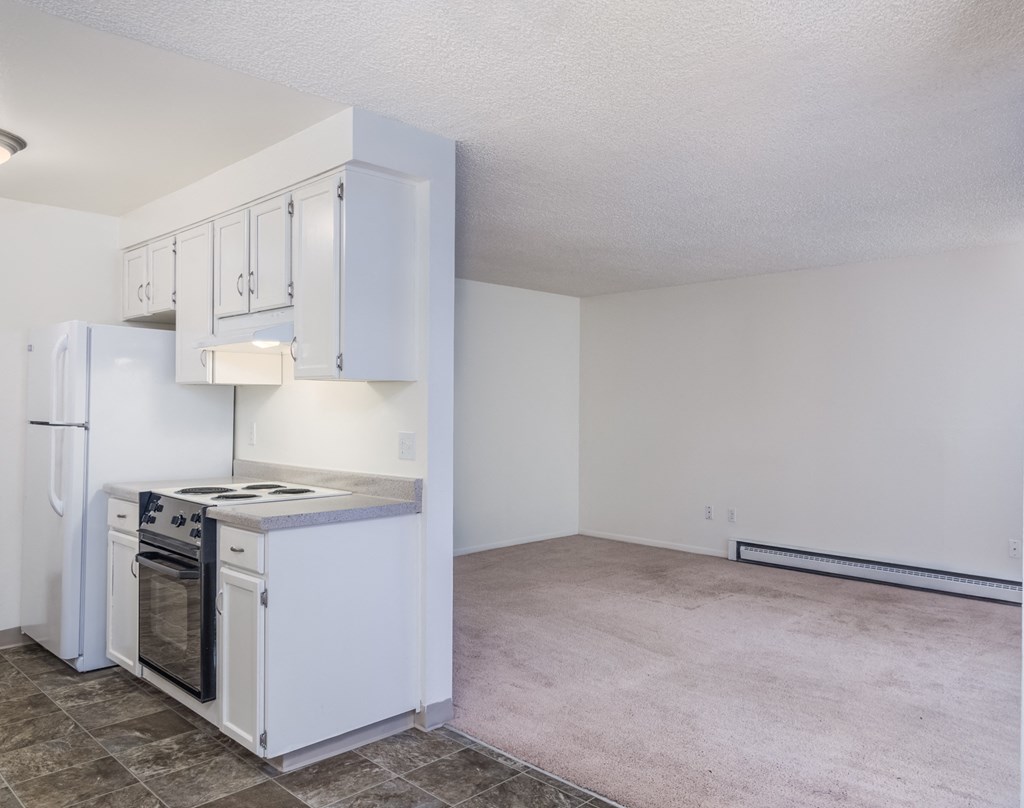 an empty kitchen with white cabinets and a stove and refrigerator