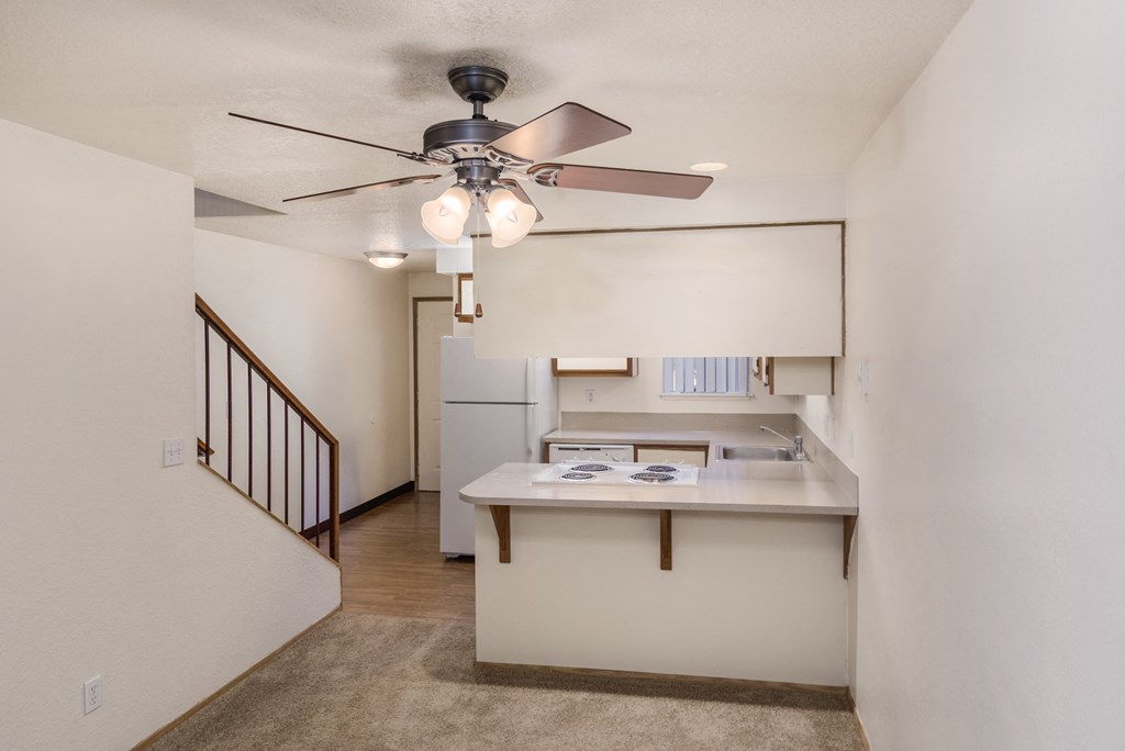 a living room with a ceiling fan and a kitchen