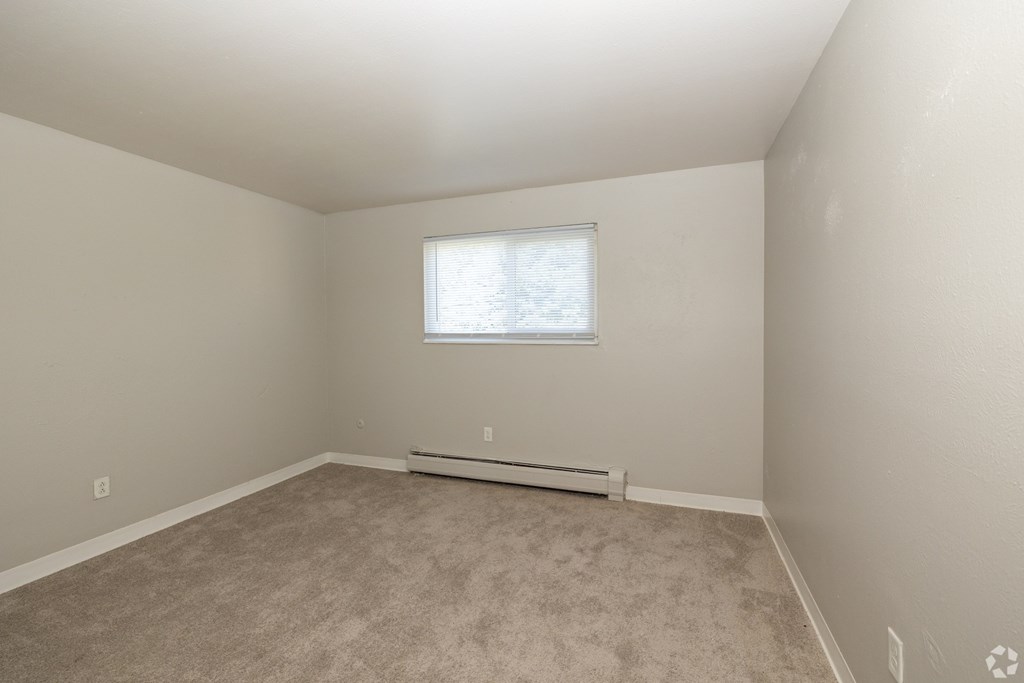 A room with a window and a radiator on the floor.