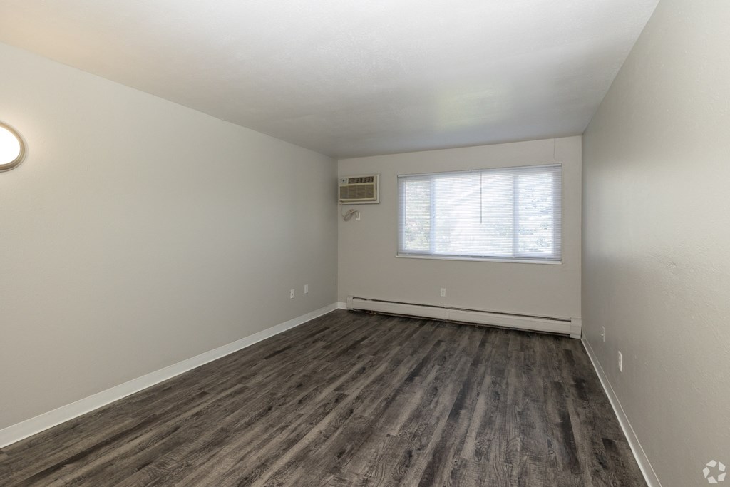 A room with a window and a wooden floor.